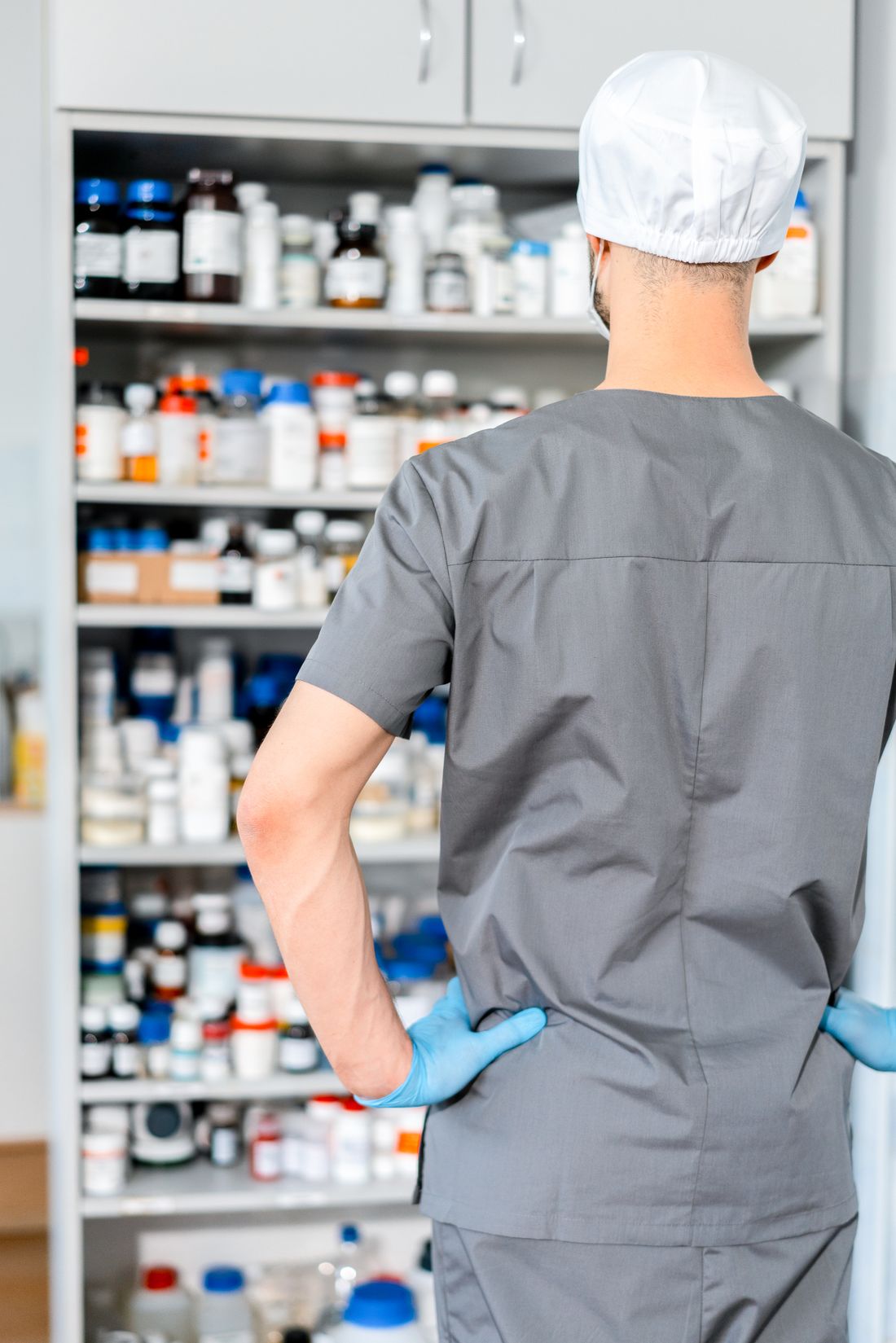 Profesional de farmacia organizando medicamentos en estanterías para gestionar existencias y pedidos
